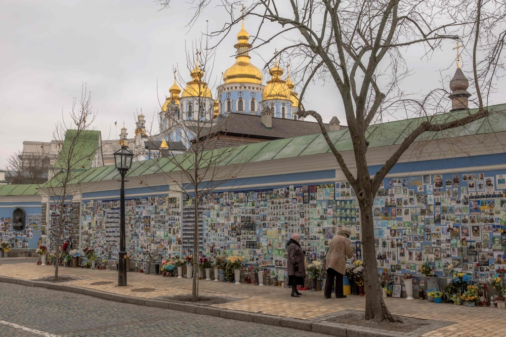 People visit ‘The Wall of Remembrance of the Fallen for Ukraine’, a memorial for Ukrainian soldiers, as the Holy Dormition Kyiv Caves Lavrain is seen in background in downtown Kyiv, on February 23, 2024, ahead of the second anniversary of Russia's invasion of Ukraine. — AFP pic