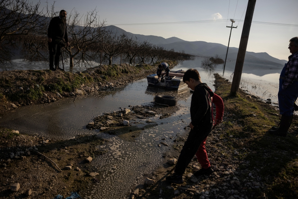 Fisherman Yiannis Tsiantos, 59, farmer Babis Evangelinos, 67, and father Athanasios Skopianos 49, stand next to the flooded area which used to be farmland, following the extreme flooding of last September, in the village of Kanalia, Greece, February 17, 2024. — Reuters pic