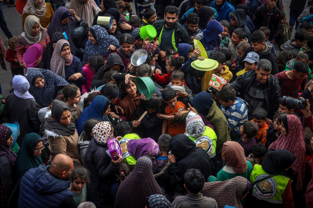 Displaced Palestinians gather to receive food at a government school in Rafah in the southern Gaza Strip on February 19, 2024, amid the ongoing battles between Israel and the militant group Hamas. — AFP pic