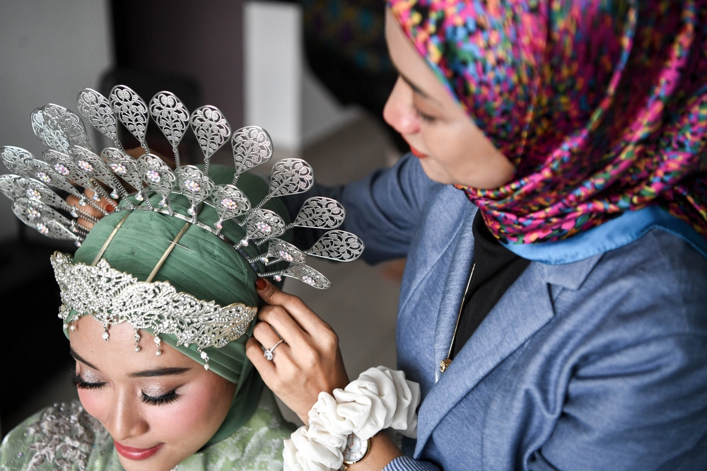 Hijab stylist Nursalihah Ahmad Azman Saha, 34, putting the final touches on a bride's headgear. — Bernama pic