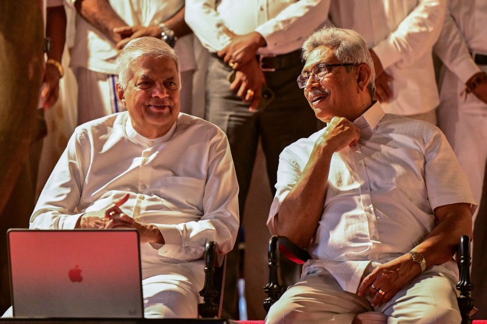 Sri Lanka’s President Ranil Wickremesinghe (left) speaks with Sri Lanka’s former President Gotabaya Rajapaksa as they attend the annual Buddhist Navam procession to mark the Navam Perahera festival in Colombo. — AFP pic