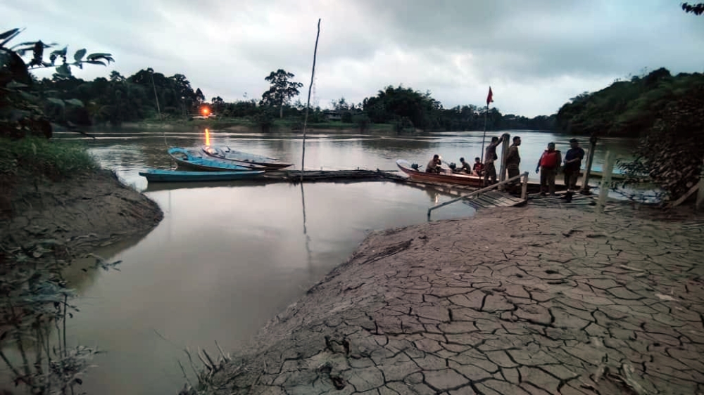 Longhouse residents gather at the jetty as Bomba assesses the situation. — Picture via Facebook/Kanowit Fire and Rescue Department