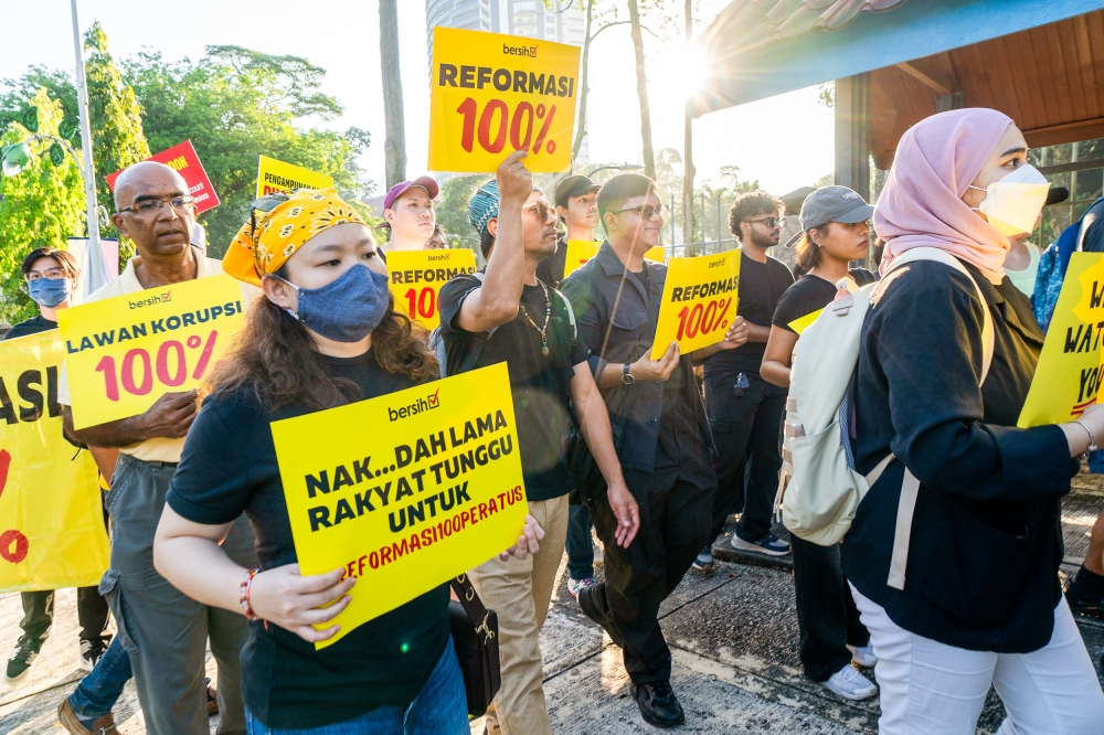 Protesters hold placards as they march towards the Parliament building in Kuala Lumpur February 27, 2024. ― Picture by Shafwan Zaidon