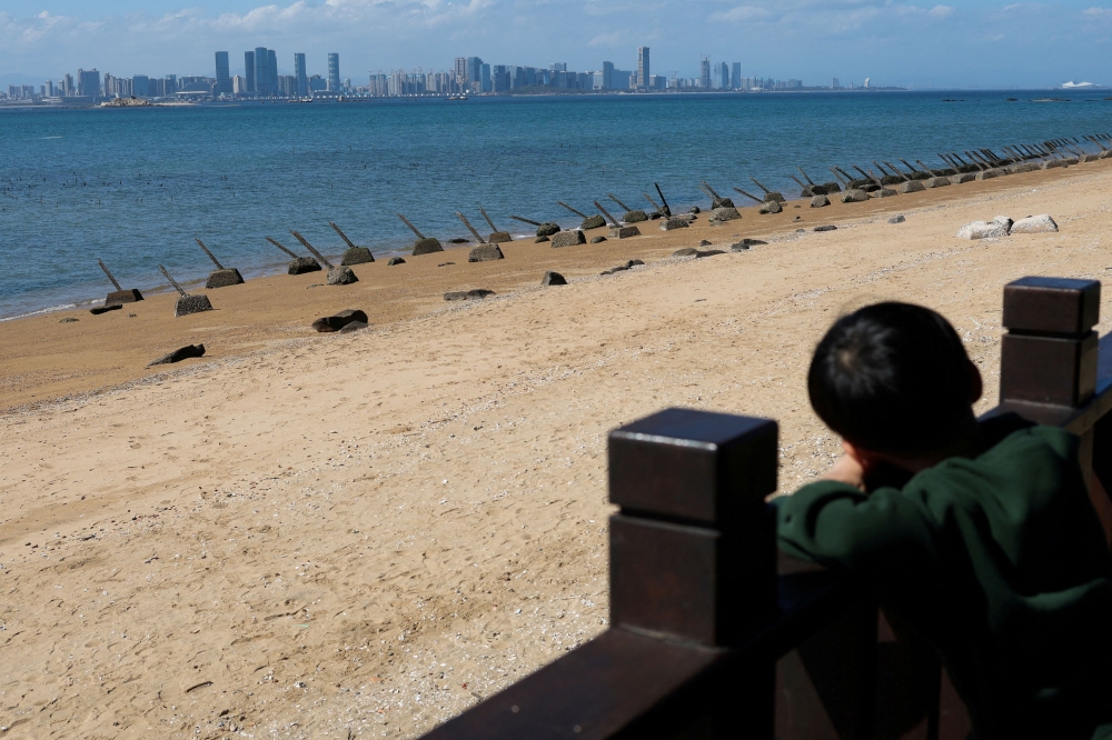 A child looks on towards China's Xiamen city from the coast in Kinmen, Taiwan February 21, 2024. — Reuters pic