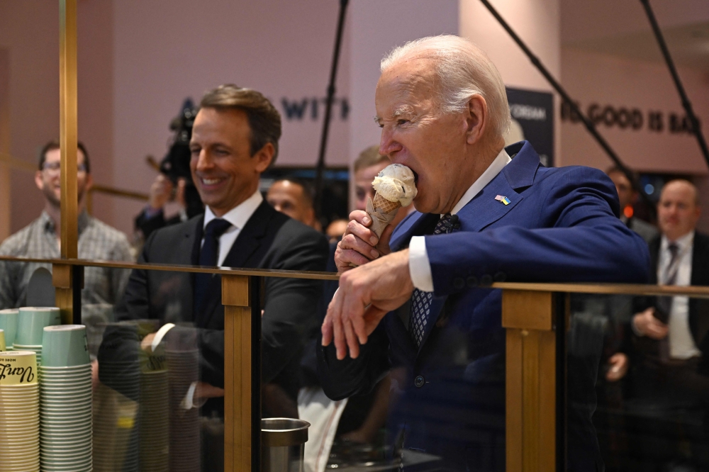 US President Joe Biden (right), flanked by host Seth Meyers (left), eats an ice cream cone at Van Leeuwen Ice Cream after taping an episode of ‘Late Night with Seth Meyers’ in New York  February 26, 2024. — AFP pic