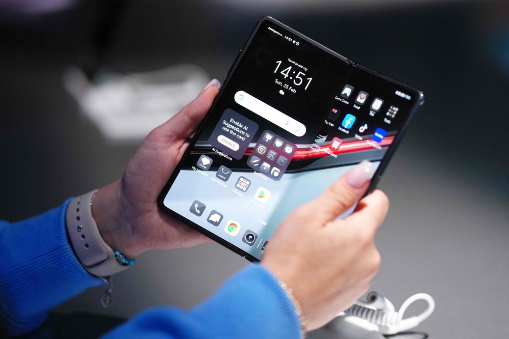 A woman holds the new Honor Magic V2 RSR smartphone, a device with the partnership of the German cars manufacturer Porsche, during a presentation on the eve of the Mobile World Congress (MWC), the telecom industry's biggest annual gathering, in Barcelona February 25, 2024. — AFP pic