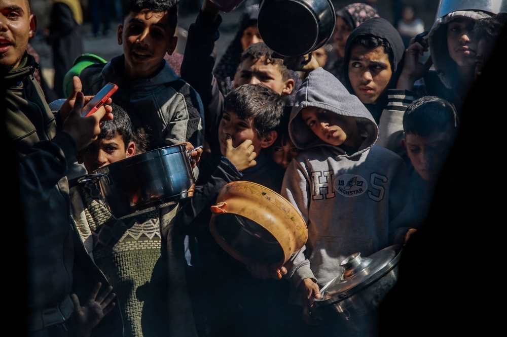Palestinian children wait to get food from an aid distribution team in Beit Lahia, northern Gaza. — AFP pic