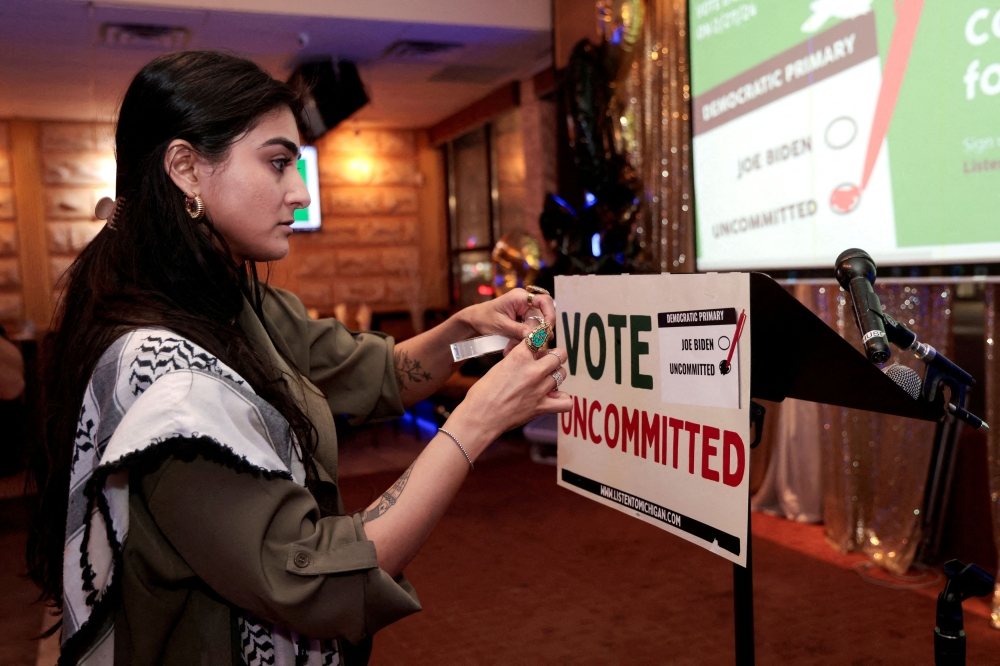 Activist Natalia Latif tapes a Vote Uncommitted sign on the speaker's podium during an uncommitted vote election night gathering as Democrats and Republicans hold their Michigan primary presidential election, in Dearborn, Michigan February 27, 2024. — Reuters pic