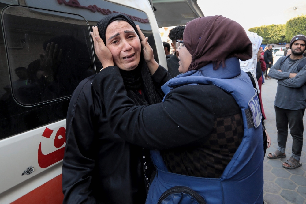A member of the press consoles a woman outside Al-Aqsa hospital in Deir el-Balah in central Gaza. — AFP pic