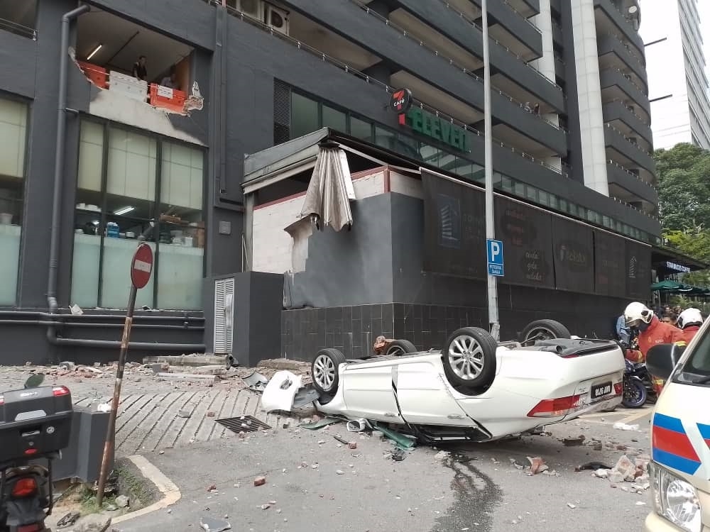 The white Honda Accord crashed through the barrier wall of the parking lot at TA One Tower before plummeting onto the pavement below. — Picture courtesy of Malaysian Fire and Rescue Dept  