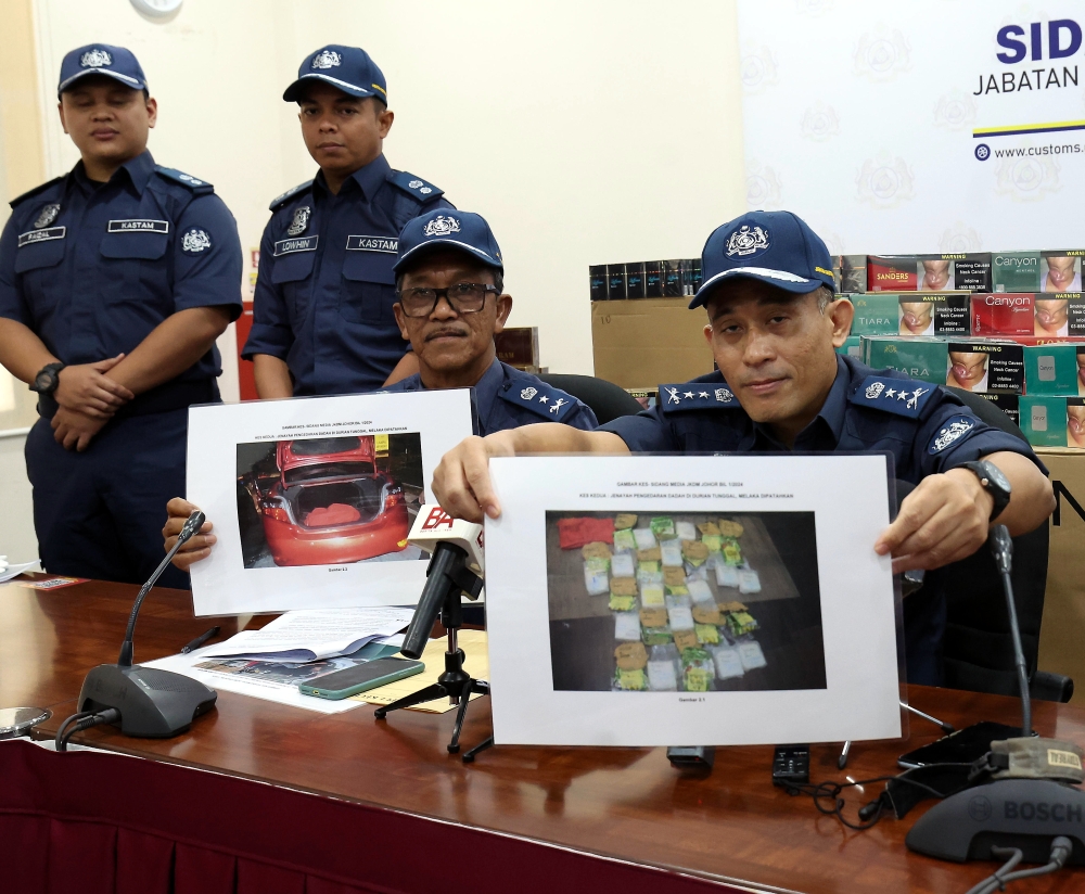 Johor Customs Department director Aminul Izmeer Mohd Sohaimi (right) and his deputy Mohd Yusni Md Yunus show pictures of the seized drugs at the Sungai Pulai Customs Department Enforcement Complex, March 4, 2024. — Bernama pic 