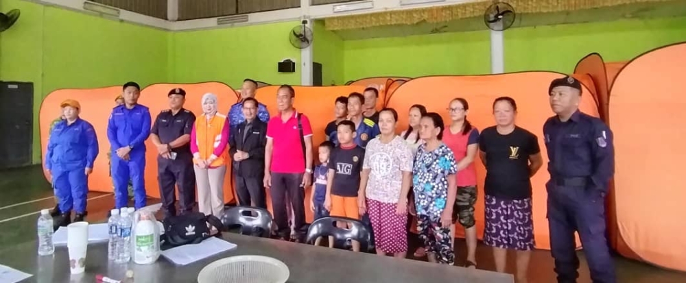 Government personnel are seen with evacuees at the Kampung Slabi Entukuh Hall PPS. — The Borneo Post pic