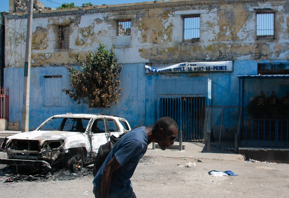 A man leaves the prison area and lowers his head because of the nearby gunfire, in Port-au-Prince, Haiti, March 4, 2024. — AFP pic
