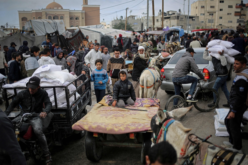 A Palestinian man transports sacks of humanitarian aid in a vehicle outside the distribution center of the United Nations Relief and Works Agency for Palestine Refugees (UNRWA), in Rafah in the southern Gaza Strip on March 3, 2024, amid the ongoing conflict between Israel and the Hamas movement. — AFP pic