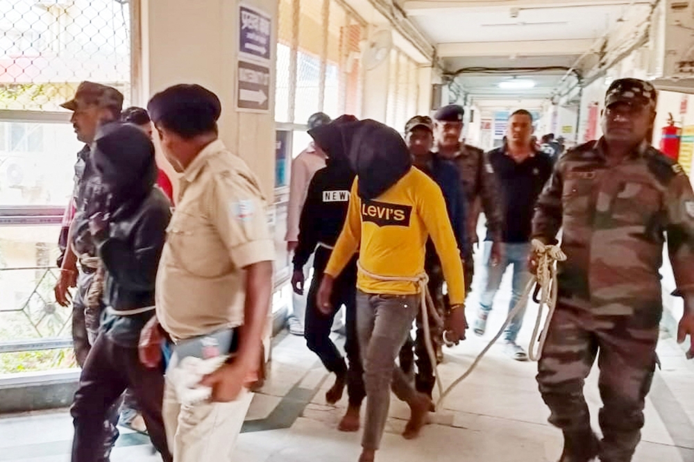 Police personnel escort men accused for allegedly carrying out a brutal assault on a Spanish woman, to a district court in Dumka, in India's Jharkhand state on March 4, 2024. — AFP pic
