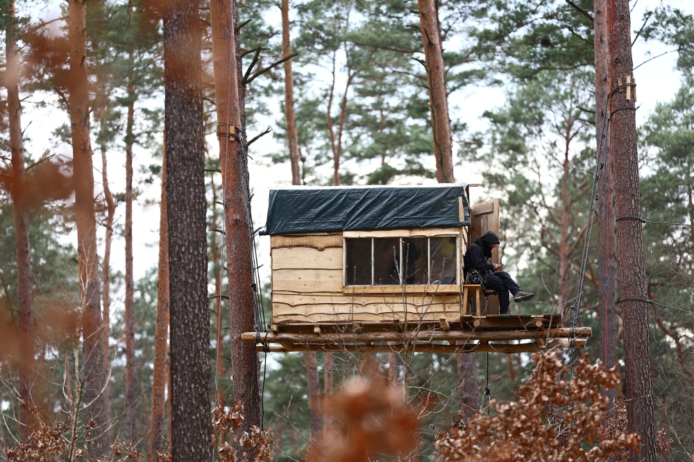 An activist sits in a tree house that is set up in a forest to protest against the expansion of the Tesla Gigafactory, in Gruenheide near Berlin, Germany, March 5, 2024. — Reuters pic