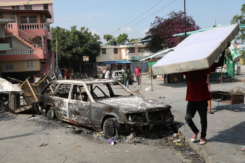 In Port-au-Prince, flames licked around a looted food warehouse and burned-out cars lined the streets. — Reuters pic
