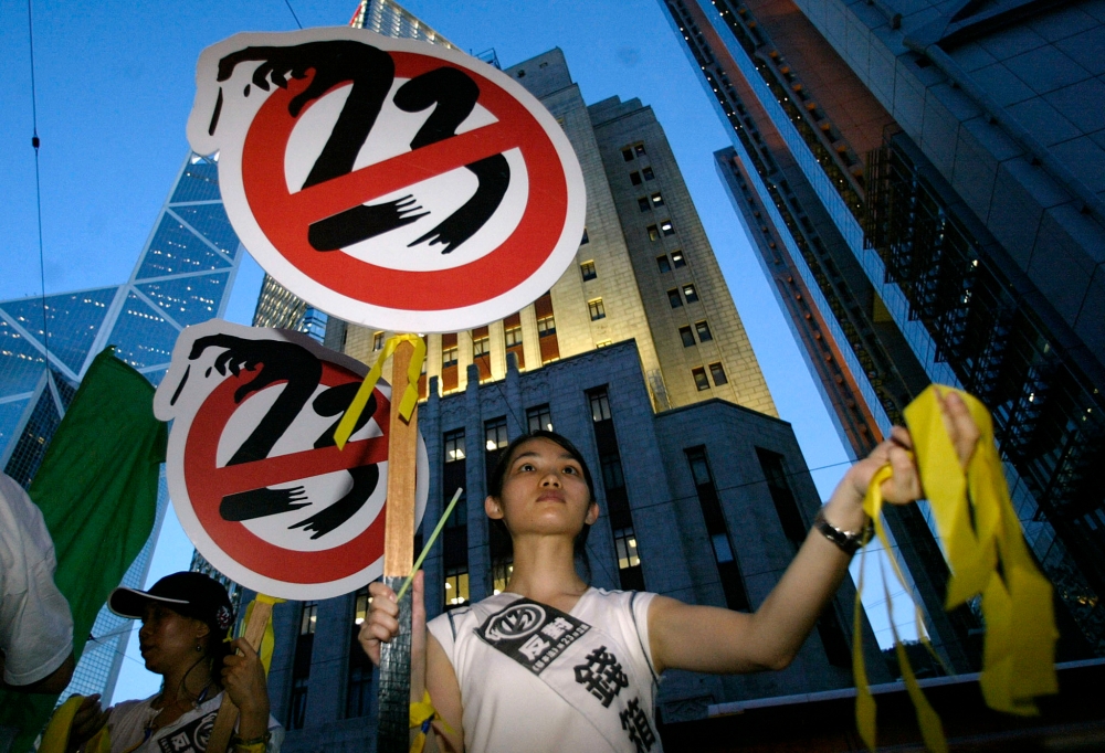 A girl hands out yellow ribbons against the controversial Article 23 law during a protest in Hong Kong on July 9, 2003. — AFP file pic