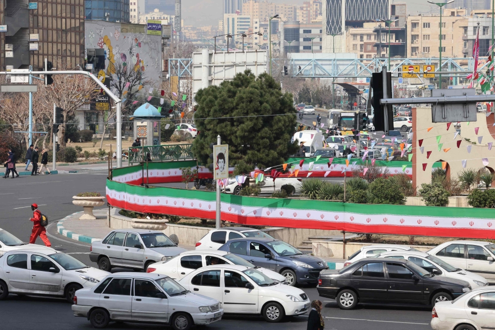 File photo of cars driving past a wall covered by a banner in the colours of the national flag in Tehran on March 3, 2024, two days after Iranians voted in the country’s parliamentary election. — AFP pic
