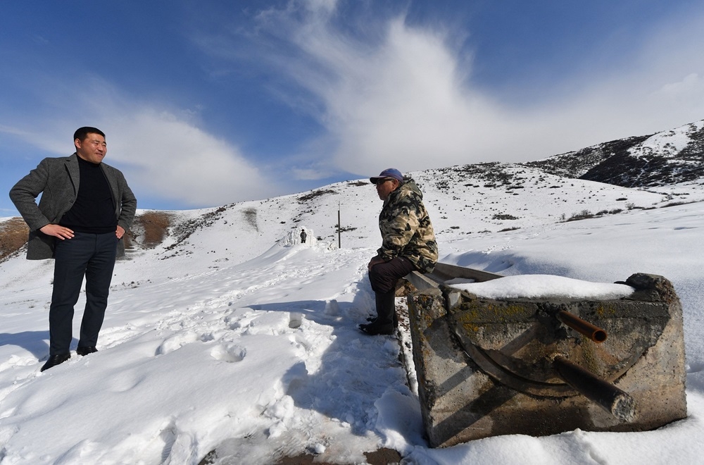 A group of men, including farmer Erkinbek Kaldanov (right), 54, and the Syn-Tash district chief Maksat Dzholdoshev (left), is seen near the artificial glacier in a mountain gorge near the village of Syn-Tash, some 60km from Bishkek. — AFP pic 