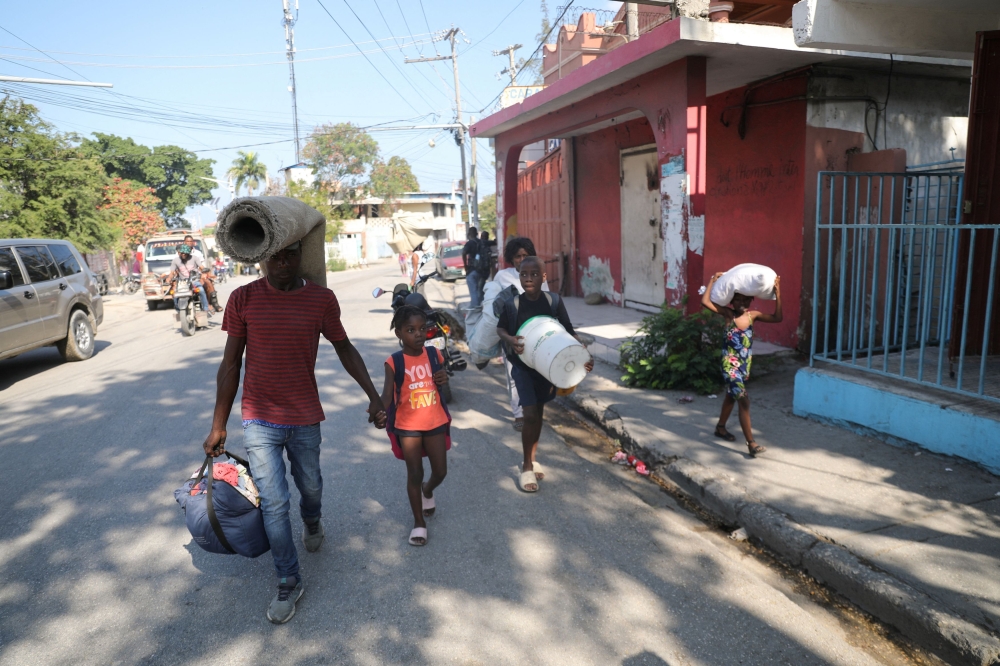 People fleeing from violence around their homes walk towards a shelter with their belongings, in Port-au-Prince, Haiti March 9, 2024. — Reuters pic