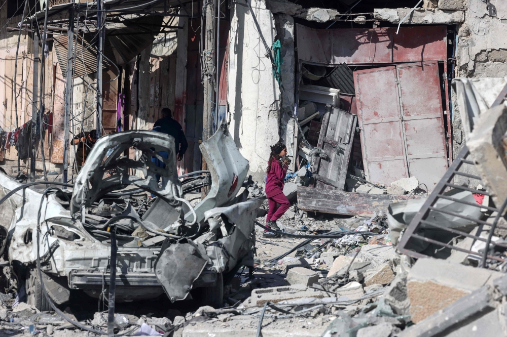 A child walks pass a building hit in an Israeli strike in Rafah. — AFP pic