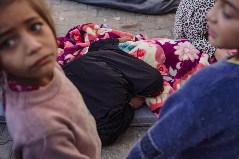 Children look on as a Palestinian woman mourns in the courtyard of the Al-Aqsa Martyrs Hospital in Deir Al-Balah in the central Gaza. — AFP pic