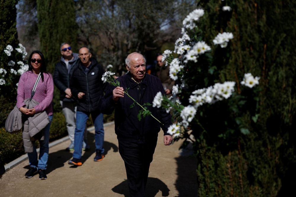A man holds flowers, as he pays a tribute to the victims of the March 11, 2004 train bombings, on the 20th anniversary, at Retiro park in Madrid, Spain, March 11, 2024. — Reuters pic
