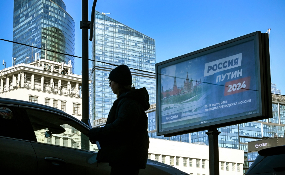 A person walks past a campaign poster of Russian President and presidential candidate Vladimir Putin in western Moscow on March 12, 2024. — AFP pic