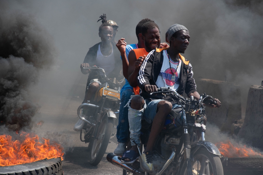 Men on motorcycles drive past by burning tires during a demonstration following the resignation of its Prime Minister Ariel Henry, in Port-au-Prince, Haiti, on March 12, 2024.  — AFP pic