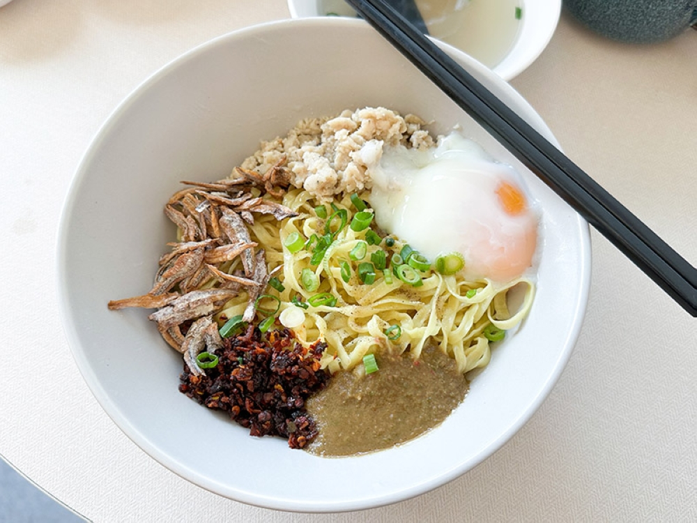 Spicy Chilli Hakka Mee is a winner with its slightly chewy strands mixed with a poached egg, minced chicken, dried red chillies 'sambal', fried ikan bilis and a spicy green chilli sauce