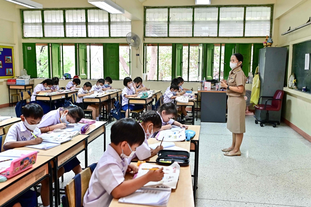 This photo taken on January 22, 2024 shows pupils wearing face masks inside a classroom with open windows at Suanlumpinee School in Bangkok. — AFP pic