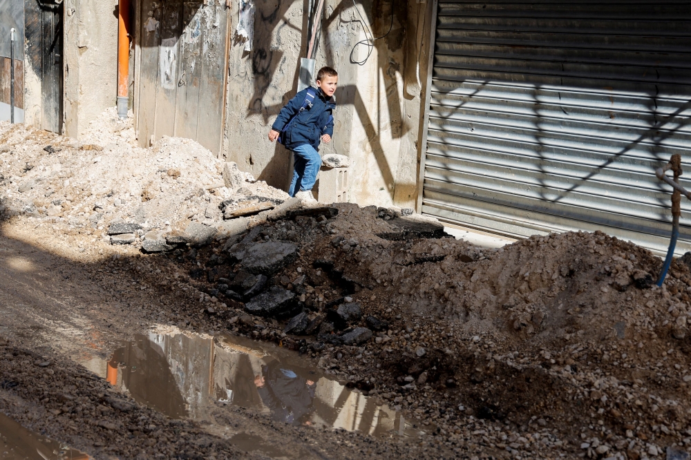 A Palestinian child walks on a damaged road, following a military operation by the Israeli army, in Jenin camp, in the Israeli-occupied West Bank, March 13, 2024. — Reuters pic