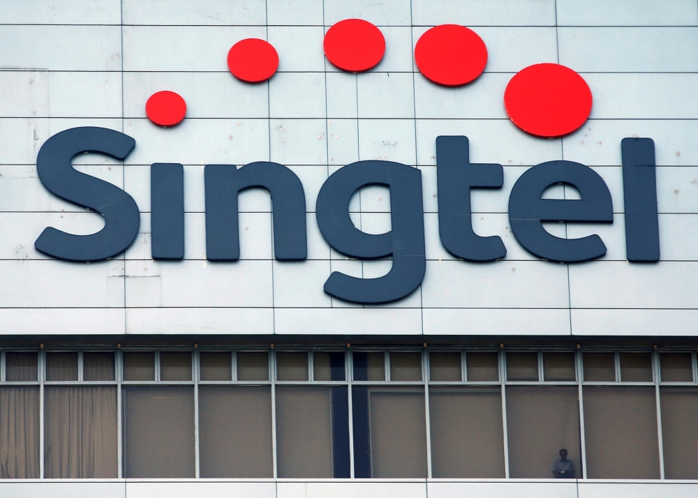A man looks out of the window under a Singtel signage at their head office in Singapore February 12, 2015. — Reuters pic  
