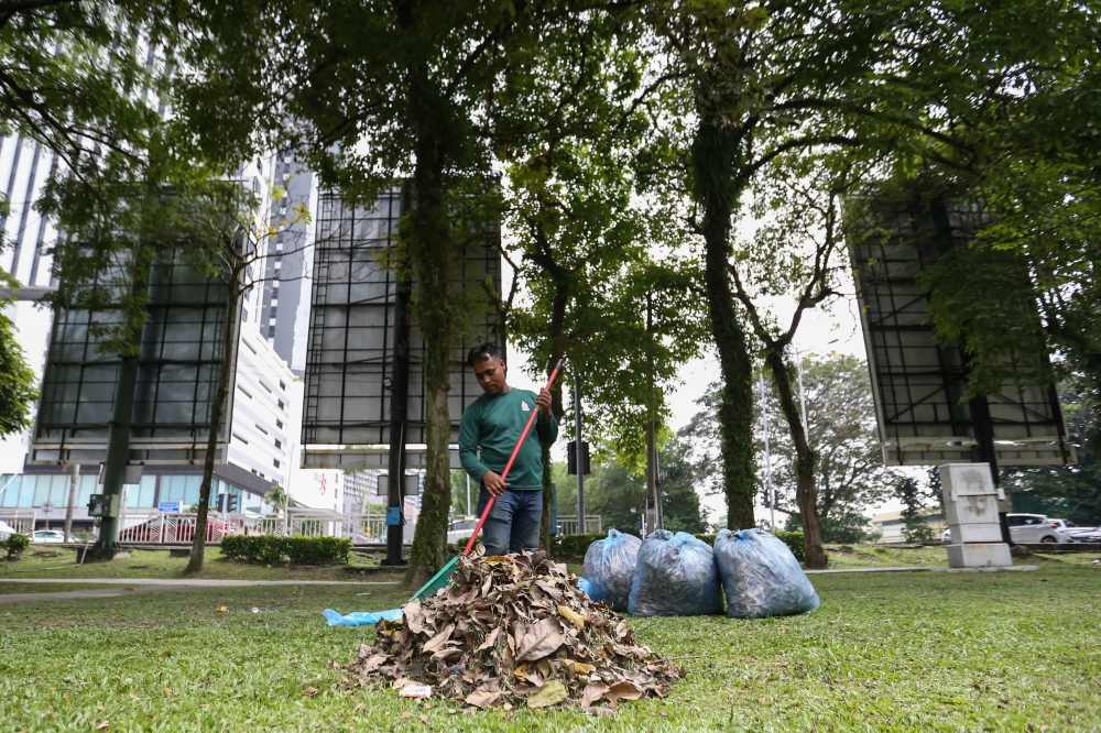 Foreign worker Sulaiman sweeps dried leaves on the first day of Ramadan in Petaling Jaya, March 12, 2024. — Picture by Miera Zulyana