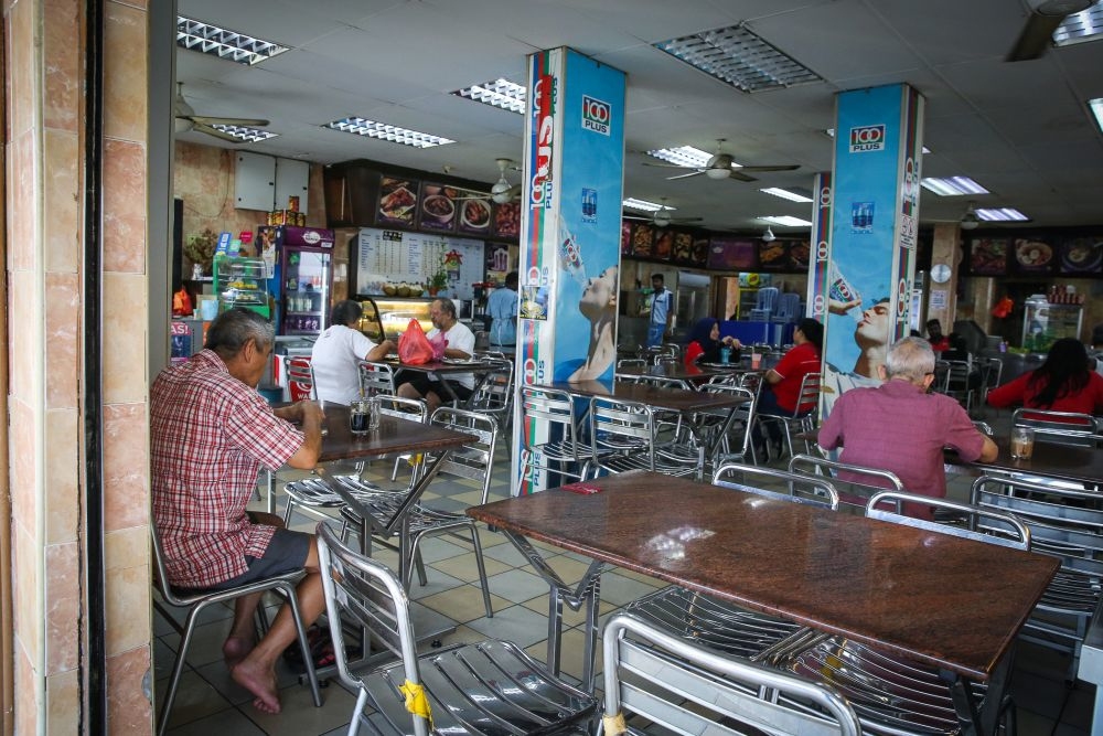 Patrons are seen eating at a mamak shop. — Picture by Shafwan Zaidon