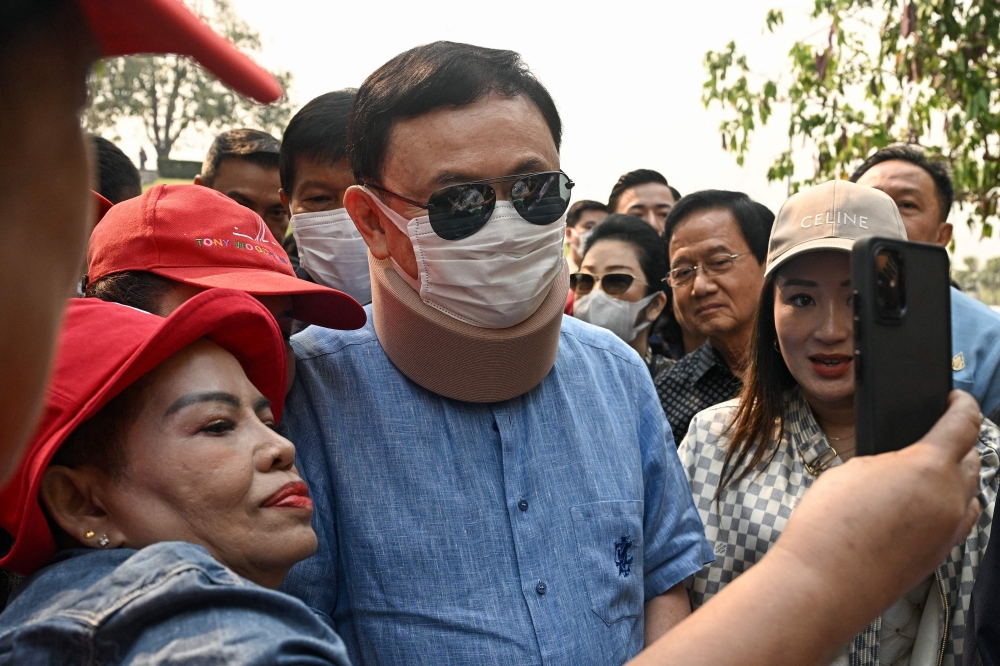 Thailand’s former prime minister Thaksin Shinawatra takes a photo with a supporter during his visit to the Royal Park Rajapruek in Chiang Mai with his daughter Paetongtarn Shinawatra today. — AFP pic