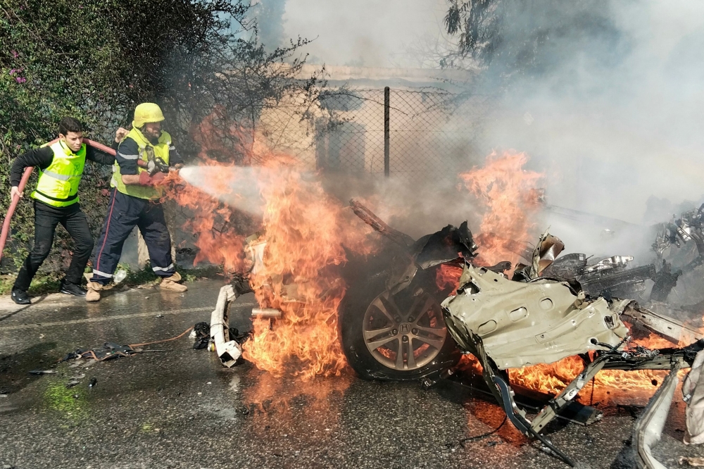 Firefighters douse a burning car after it was hit in a reported Israeli drone attack in Lebanon’s southern area of Naqoura near the border with Israel on March 13, 2024. — AFP pic