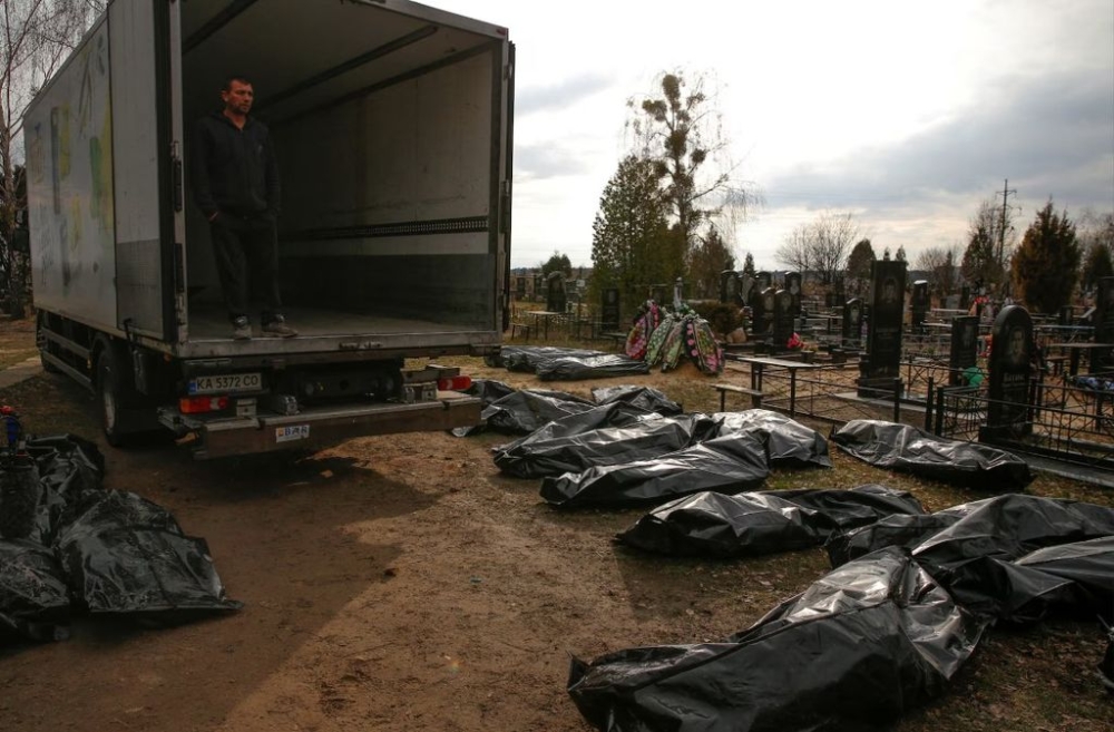 A funeral service employee looks at bodies of civilians, collected from streets and brought to a local cemetery, in the town of Bucha, outside Kyiv, Ukraine, April 6, 2022. — Reuters file pic
