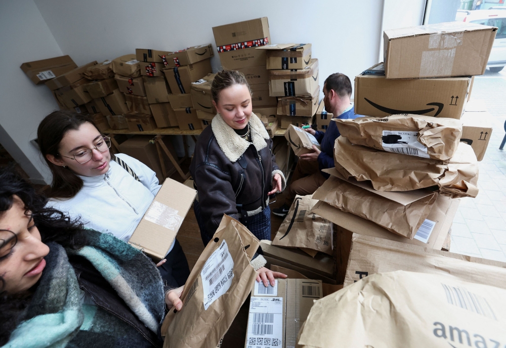 Belgian Chloe Boseret, 20, Moroccan Hiba Did, 20 and French Anouk Anglade react after opening a parcel at ‘Pile ou Face’, a shop that sells still-sealed packages, which were lost during delivery or remained uncollected at the post office, by the kilo, without knowing their contents, in Ixelles, Brussels March 15, 2024. — Reuters pic  