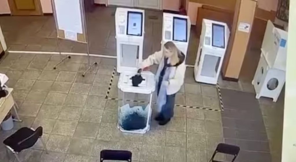 A woman pours a liquid into a ballot box, during the Russian presidential election in Moscow, Russia, in this screen grab taken from a video recording of a screen showing CCTV footage, March 15, 2024. — Video obtained by Reuters