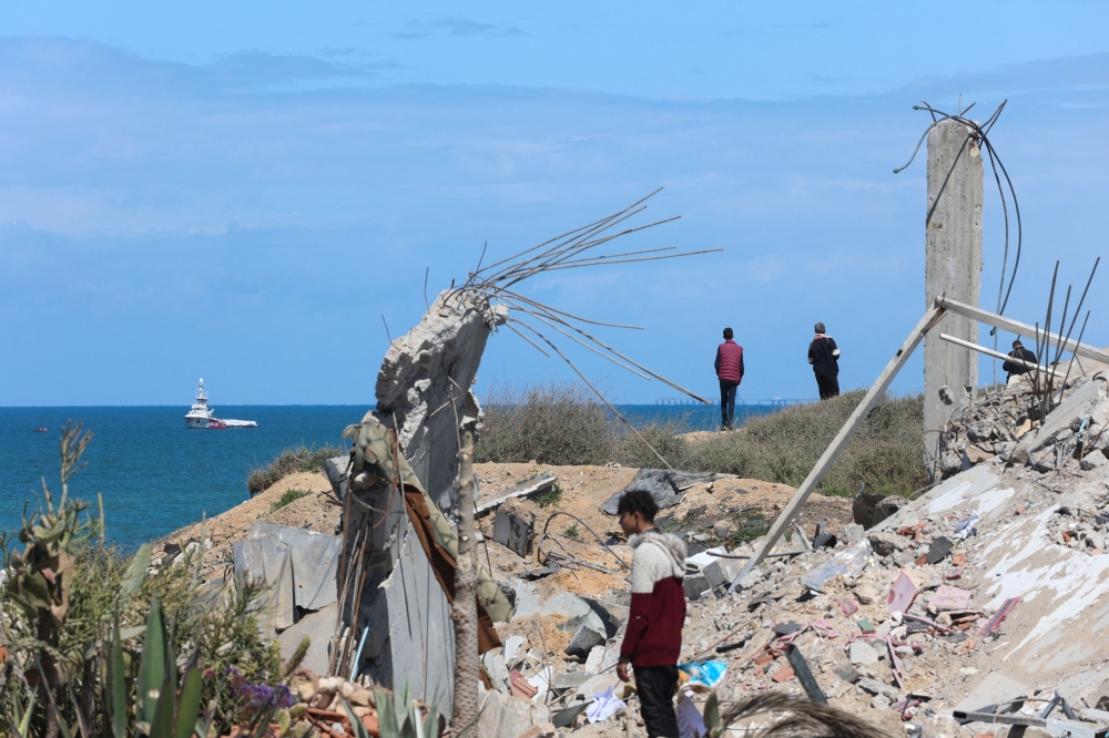 People watch as ship carrying aid sails off the shore of Gaza, amid the ongoing conflict between Israel and the Palestinian Islamist group Hamas, as seen from central Gaza Strip, March 15, 2024. — Reuters pic