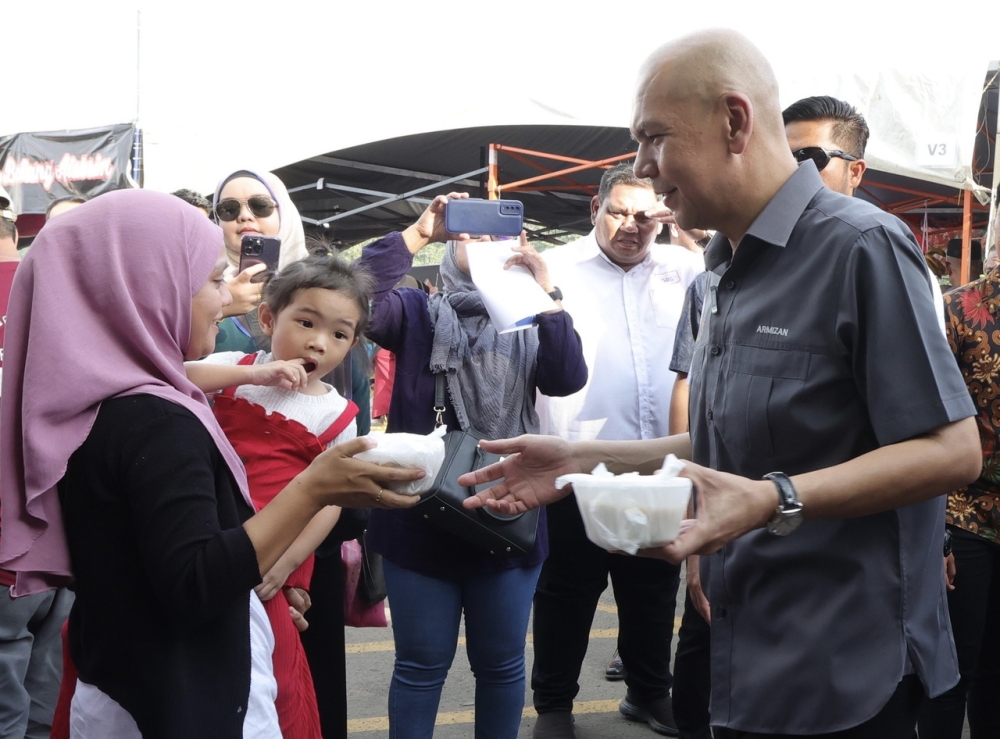 Minister of Domestic Trade and Cost of Living Datuk Armizan Mohd Ali (right) presenting a donation of bubur lambuk to the public during a visit to the Ramadan Bazaar at Tapak Tamguan, Papar, March 16, 2024. — Bernama pic