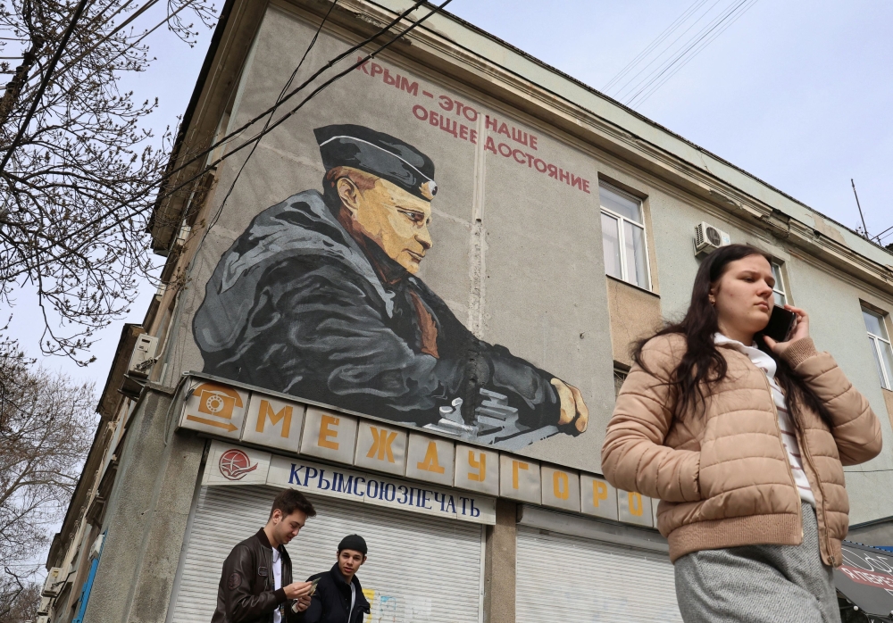 People walk along a street past a mural depicting Russian President Vladimir Putin in Simferopol, Crimea March 12, 2024. — Reuters pic
