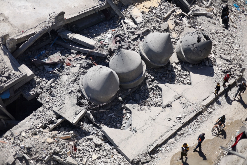 Palestinians walk pass the ruins of a destroyed mosque in Rafah. — Reuters pic