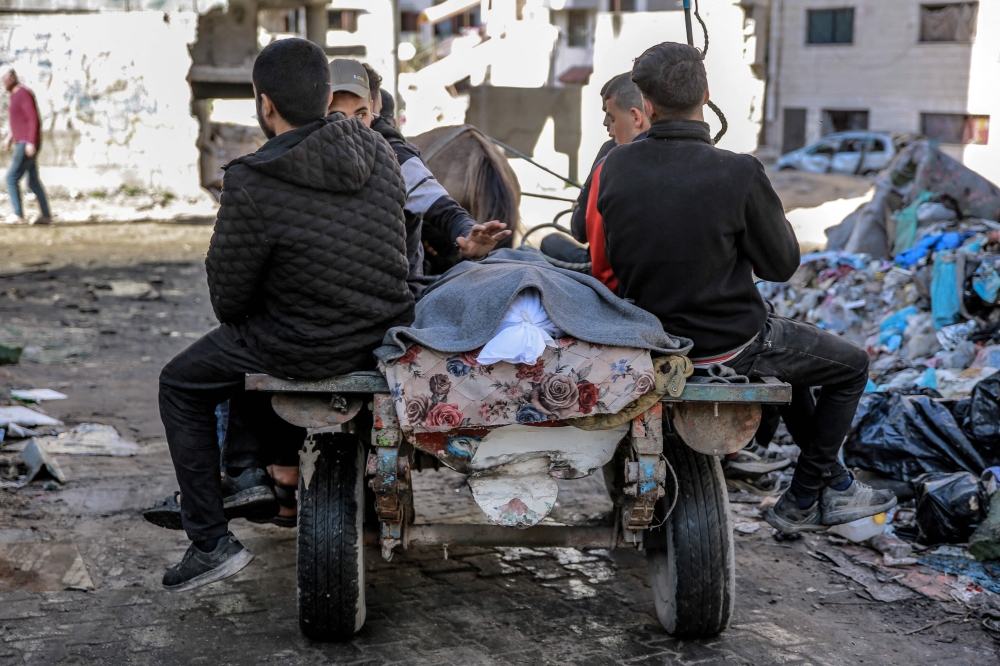 Palestinians transport the body of a relative killed in an Israeli bombardment from the morgue of the Al-Shifa hospital. — AFP pic