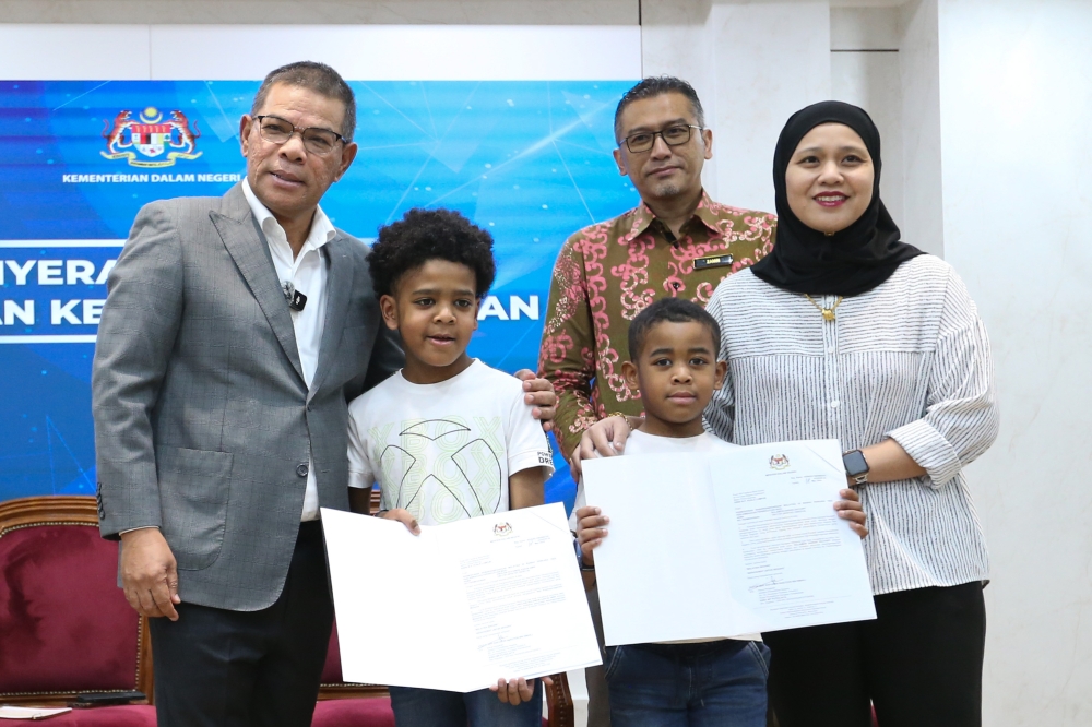 Home Minister Datuk Seri Saifuddin Nasution hands over citizenship decision letters to children born abroad to Malaysian mothers and non-citizen fathers Sulaimon Darian Zachary, 10, and Sulaimon Aaron Amir, 7, at the KDN Putrajaya headquarters March 19, 2024. — Picture by Miera Zulyana