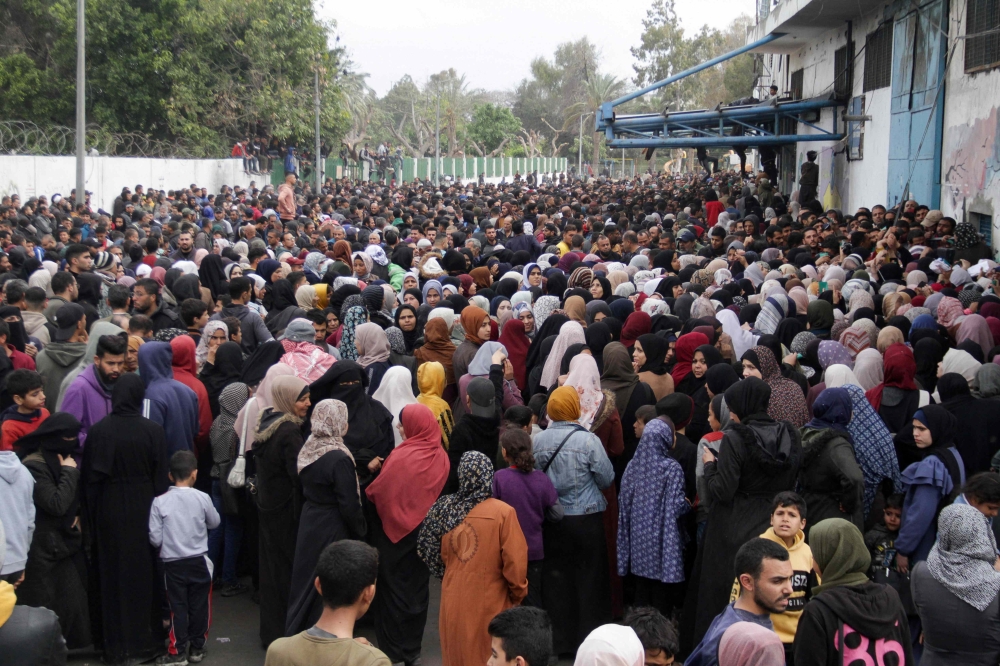 Palestinians gather to receive aid outside an UNRWA warehouse as Gaza residents face crisis levels of hunger. — Reuters pic
