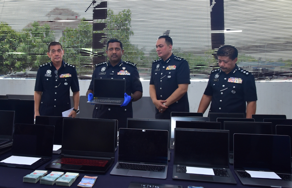 Selangor police chief Datuk Hussein Omar Khan (2nd right) shows the laptops and other items seized during a raid on a syndicate on suspicion of developing online gambling apps for foreign markets in Subang Jaya at a press conference March 21, 2024. — Bernama pic