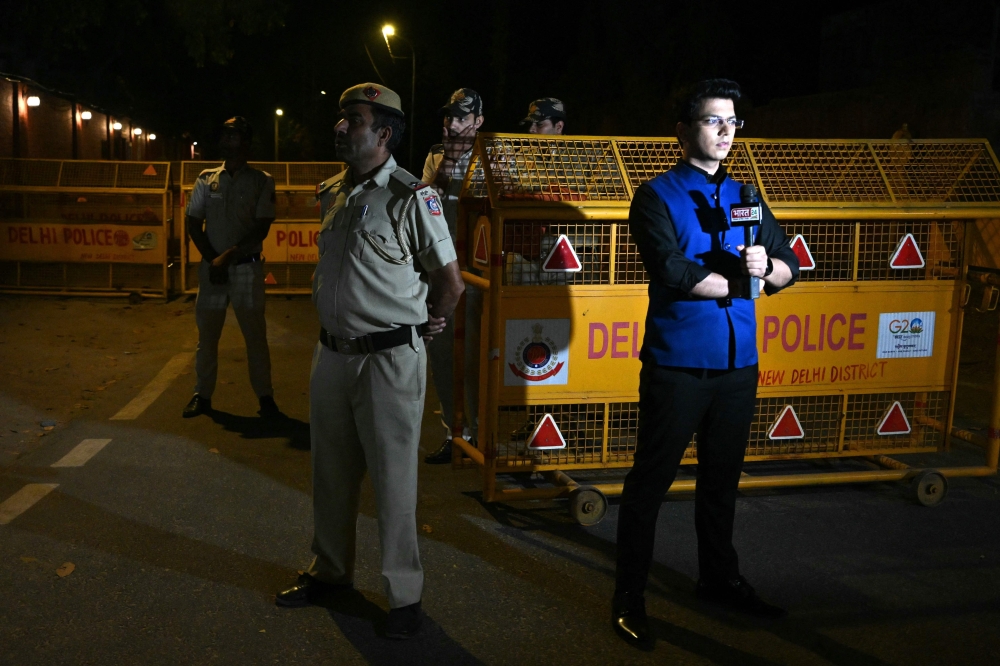 A police officer stands guard next to a journalist in front of the Enforcement Directorate, after Aam Aadmi Party chief and Delhi Chief Minister Arvind Kejriwal was arrested in a corruption case, in New Delhi on March 21, 2024. — AFP pic 